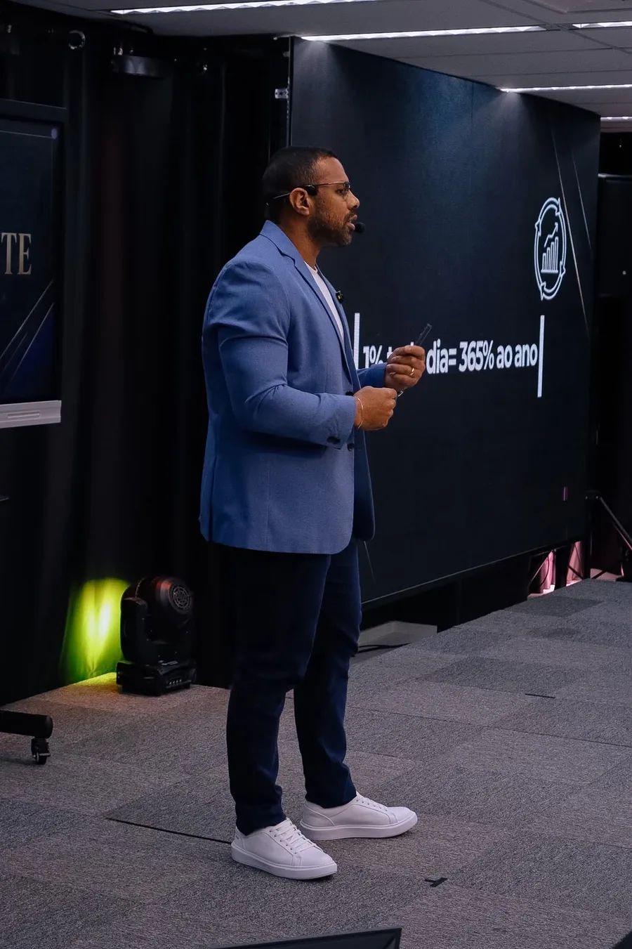 Felipe Rodrigues palestrando de blazer azul para uma plateia